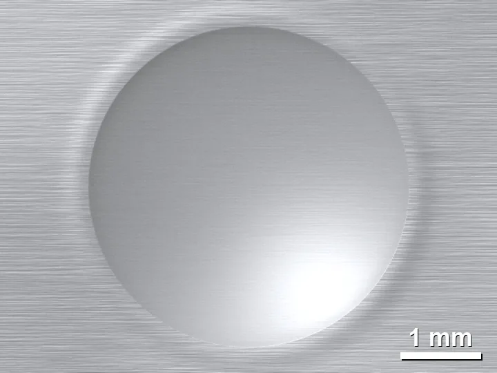 Bekas tekan bola Brinell berdiameter 4 mm pada permukaan baja yang digerinda